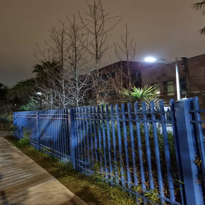 Foco solar LED 1500W instalado en poste iluminando el perímetro de un condominio de noche
